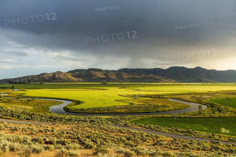 River through fields by hills in Picabo, Idaho, USA