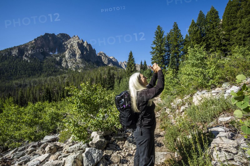 Woman photographing Sawtooth Mountains in Stanley, Idaho, USA