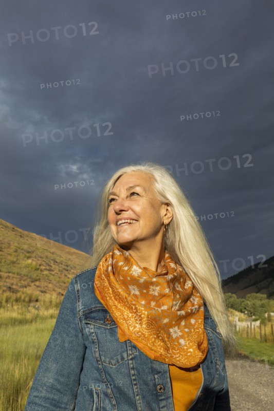 Smiling mature woman wearing orange scarf in field