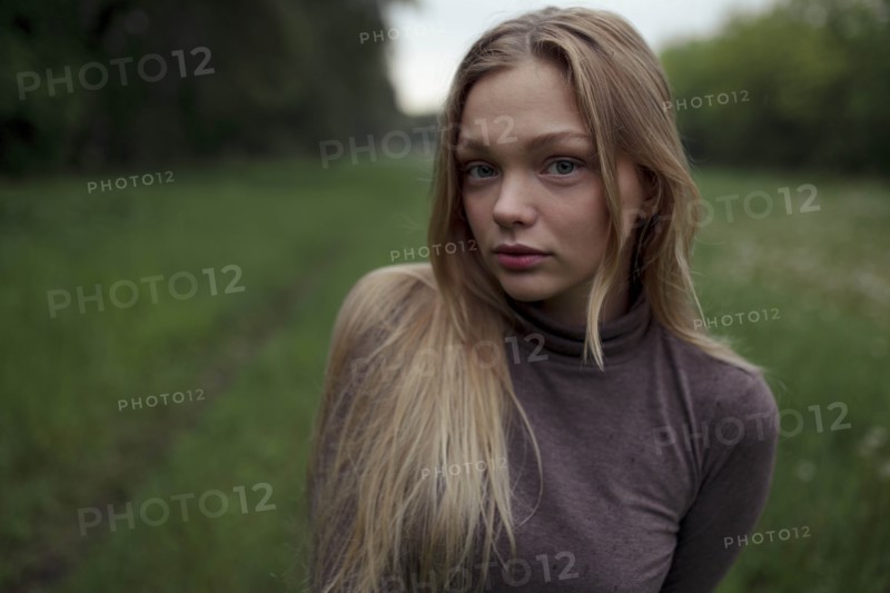 Portrait of young woman with blond hair in field