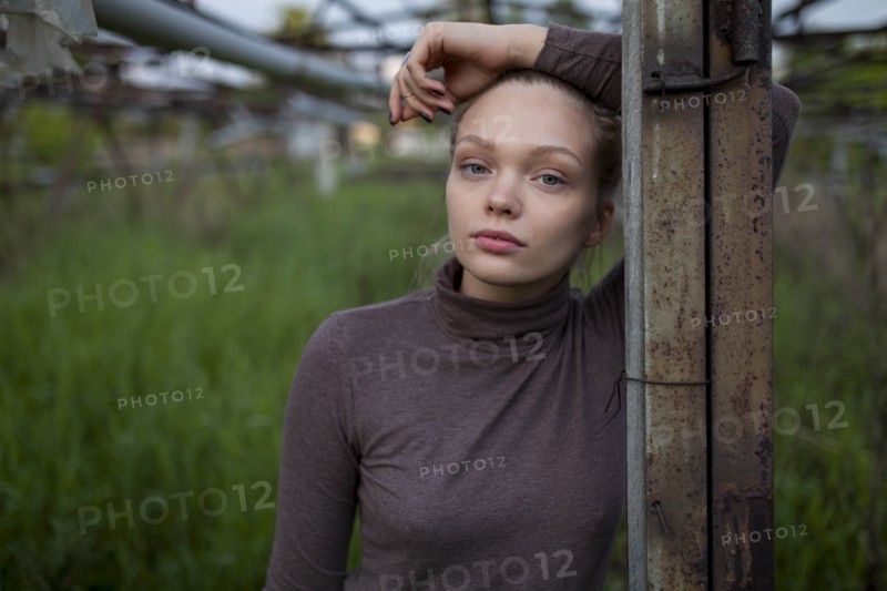 Young woman leaning on wooden post