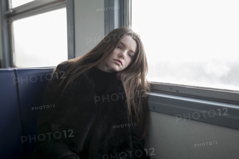 Young woman wearing black fur coat on train