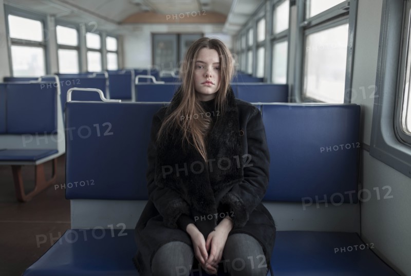 Young woman wearing black fur coat on train