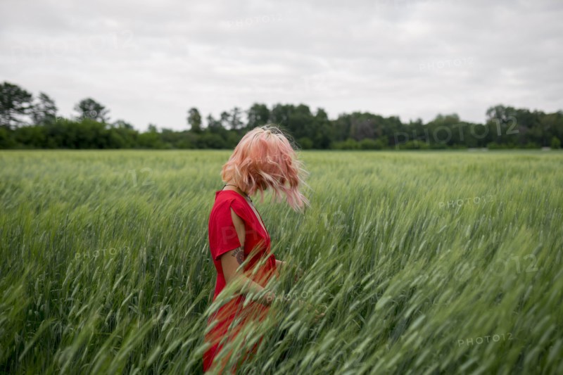 Woman with pink hair wearing red dress in wheat field