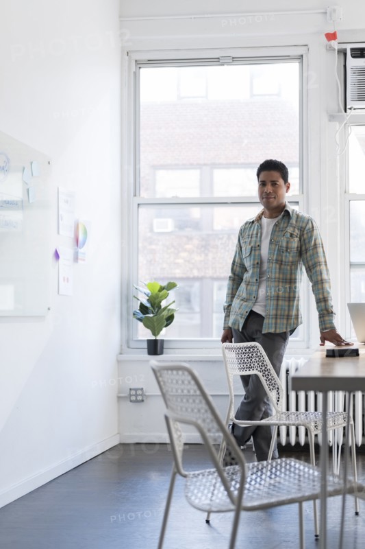 Businessman leaning on desk by whiteboard