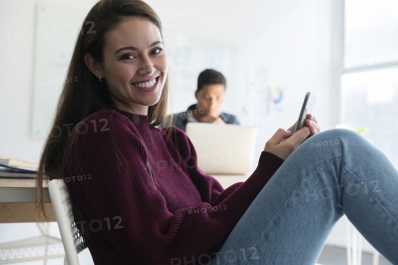 Smiling woman holding smartphone in office