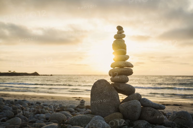 Stacked stones on beach at sunset