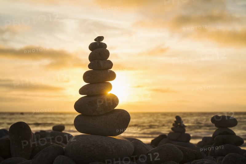 Stacked stones on beach at sunset