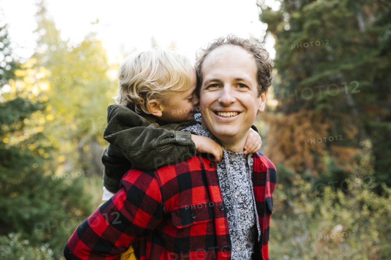 Father and son piggyback in forest