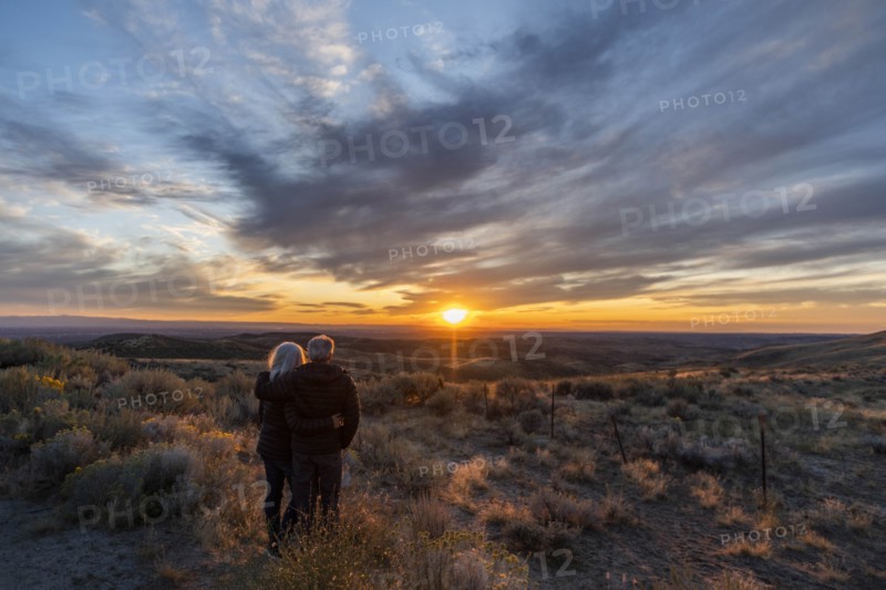 Couple in field at sunset at Boise Foothills in Boise, Idaho, USA
