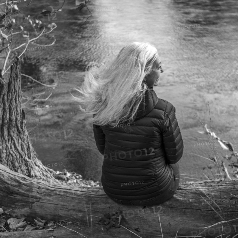 Woman sitting on log by river in Boise, Idaho, USA