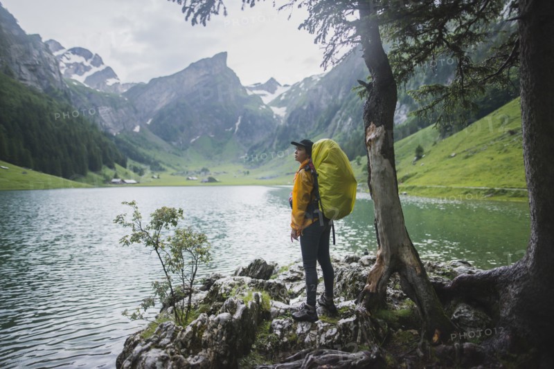 Woman wearing yellow backpack by Seealpsee lake in Appenzell Alps, Switzerland