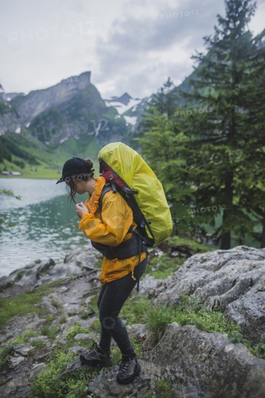 Woman wearing yellow hiking by Seealpsee lake in Appenzell Alps, Switzerland