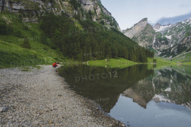 Woman crouching by Seealpsee lake in Appenzell Alps, Switzerland
