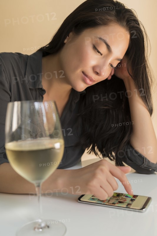 Woman using smart phone next to glass of wine