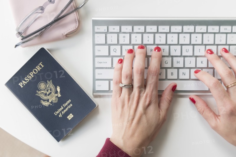 Woman typing on keyboard by passport