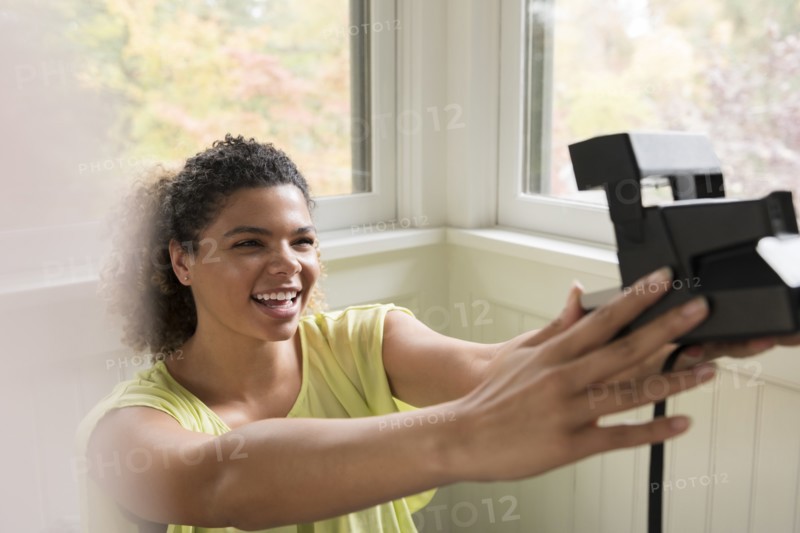 Smiling woman taking selfie with Polaroid camera