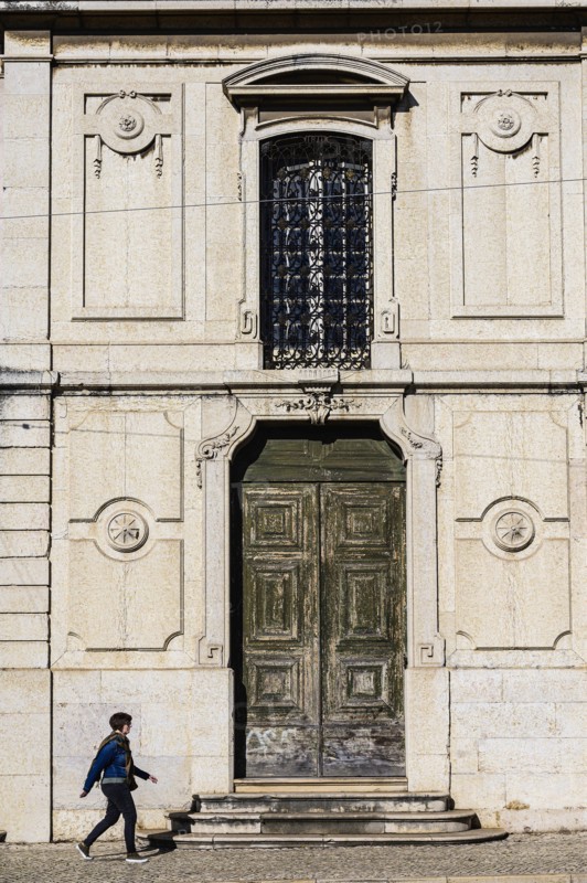 Woman walking past old building in Lisbon, Portugal