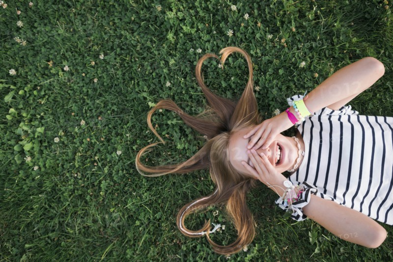 Girl with her hair in heart shapes lying on grass