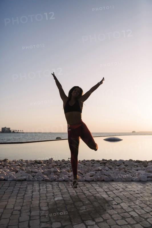 Silhouette of woman jumping at sunset