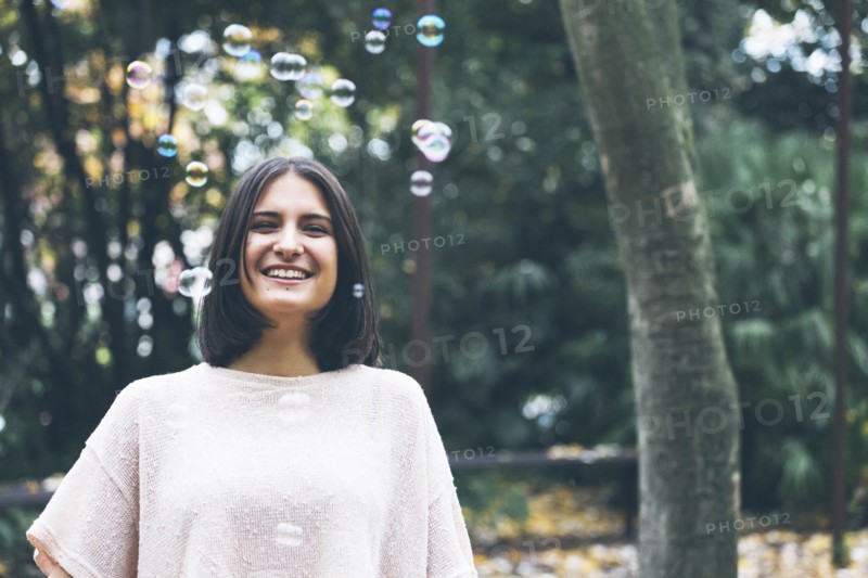 Smiling teenage girl under bubbles