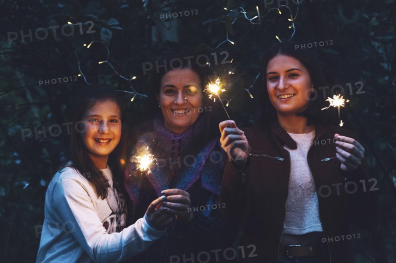 Mother and daughters smiling and holding sparklers