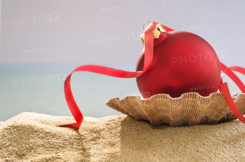 Red bauble on shell on sand