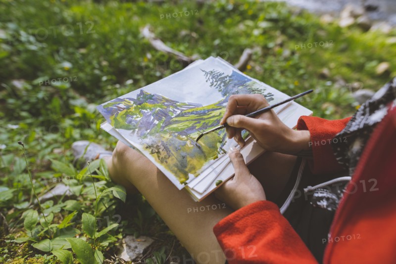 Woman painting with watercolors on grass