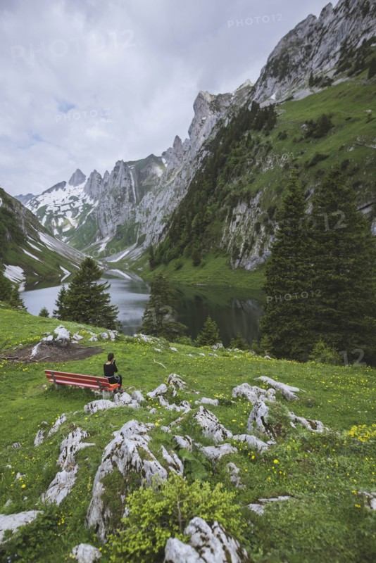 Woman sitting on bench by mountains in Appenzell, Switzerland