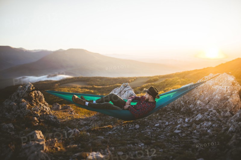 Man lying on hammock in mountain range