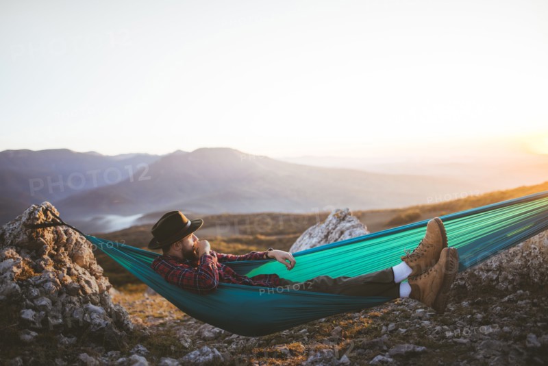Man lying on hammock in mountain range