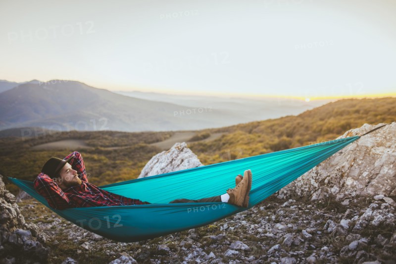 Man lying on hammock in mountain range