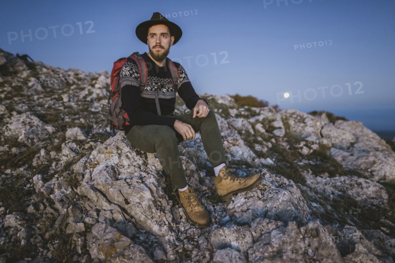 Man sitting on rock at sunset