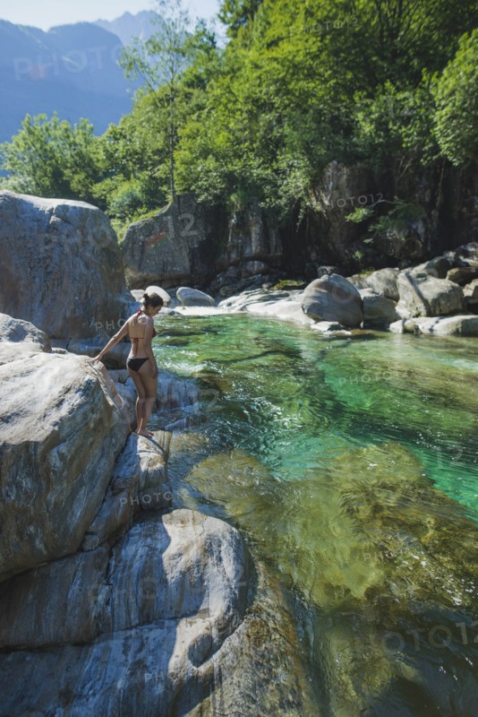 Woman wearing bikini on rock by river