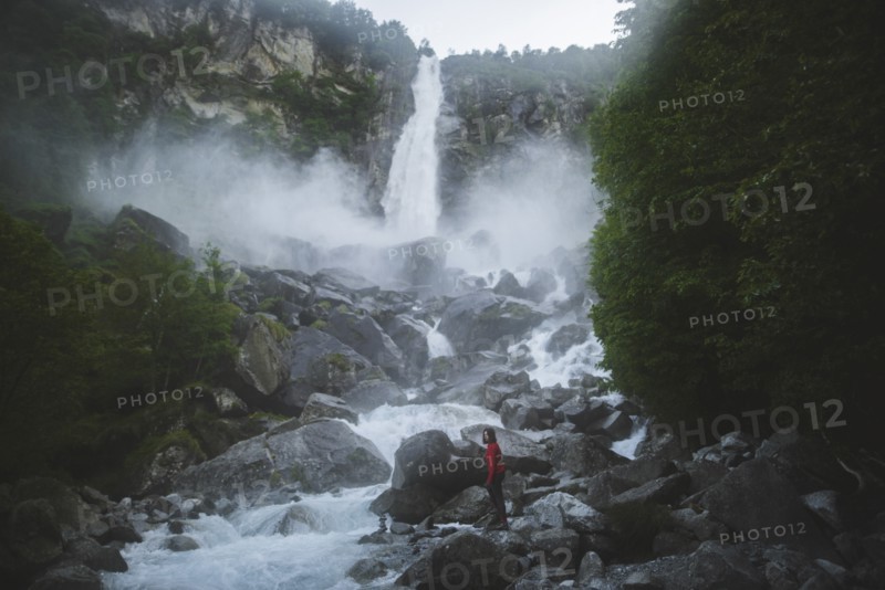 Woman on rocks by waterfall