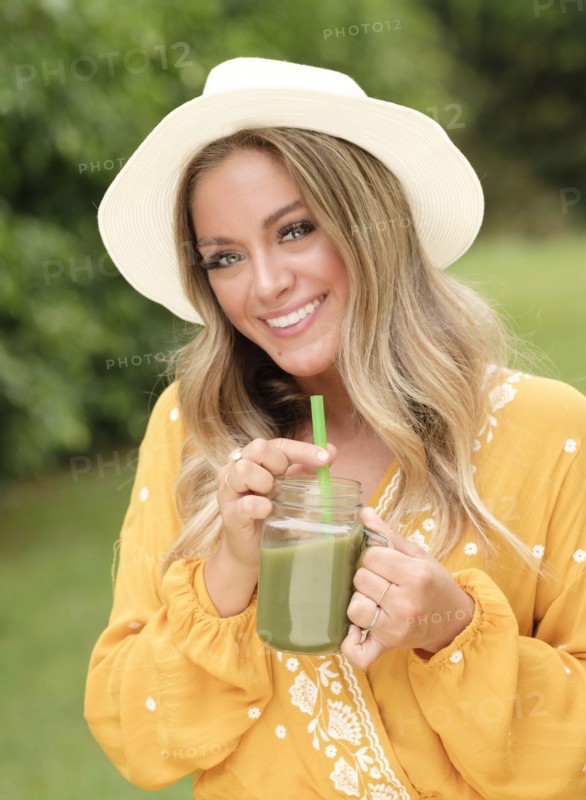 Smiling young woman with smoothie in mason jar