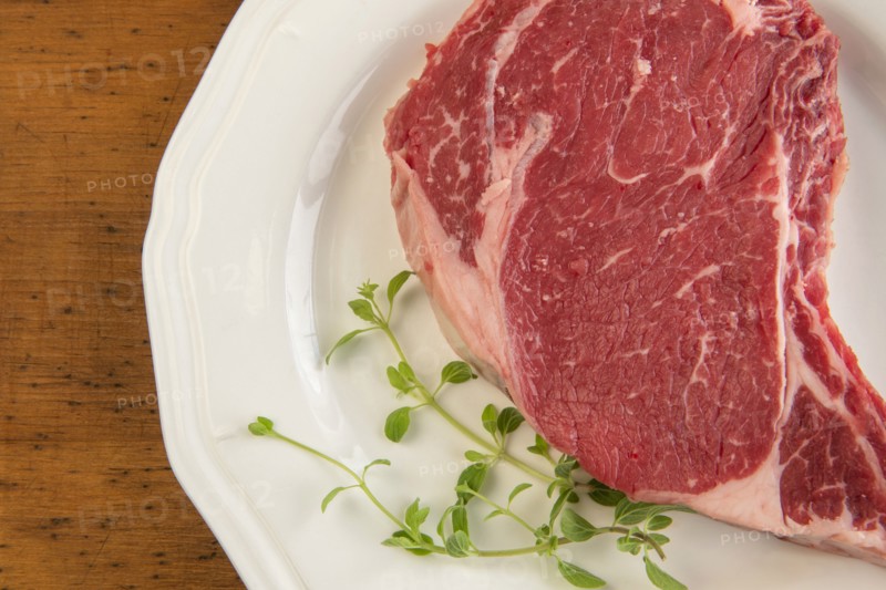 Raw steak and oregano on plate