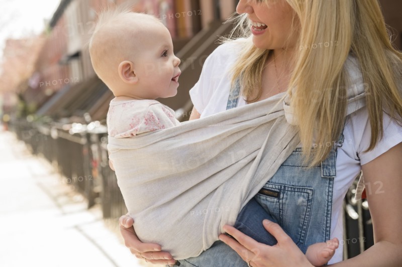 Mother carrying her daughter in baby carrier