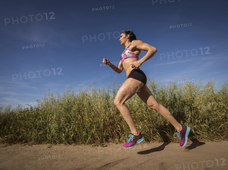 Mid adult woman jogging on path through field