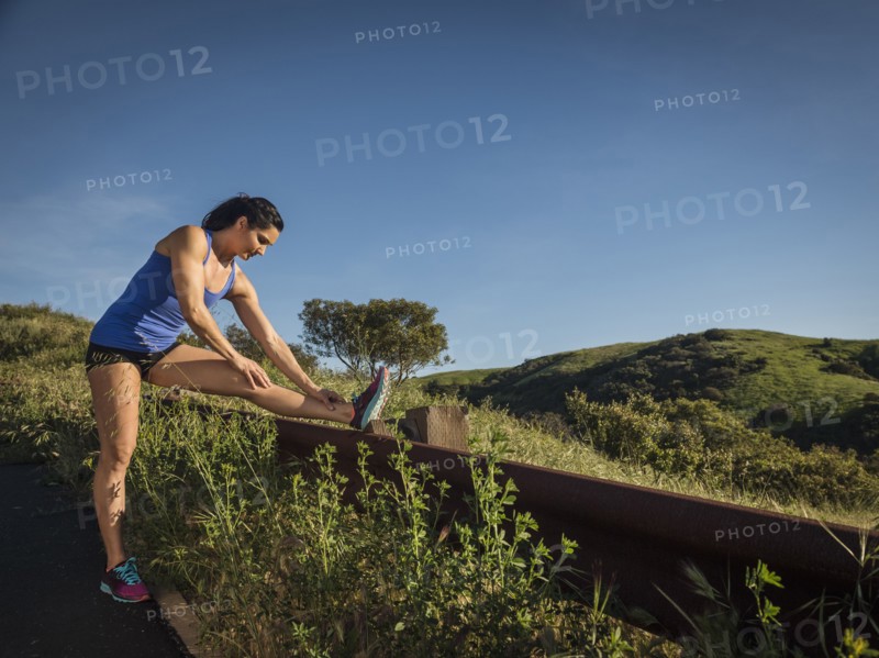 Woman in sportswear stretching on fence