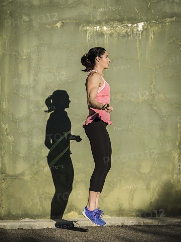 Woman skipping by concrete wall