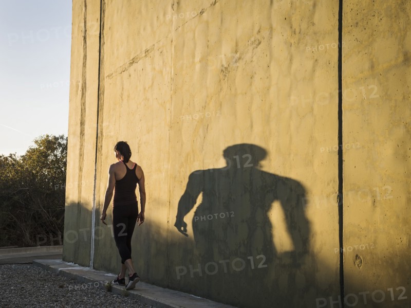 Woman in sportswear walking by concrete wall