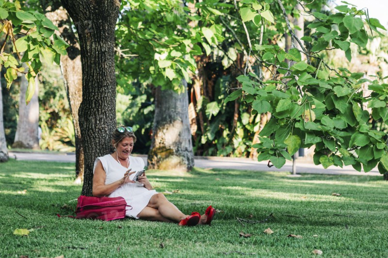 Woman using smart phone under tree