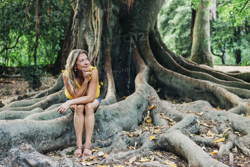 Woman sitting on roots of tree