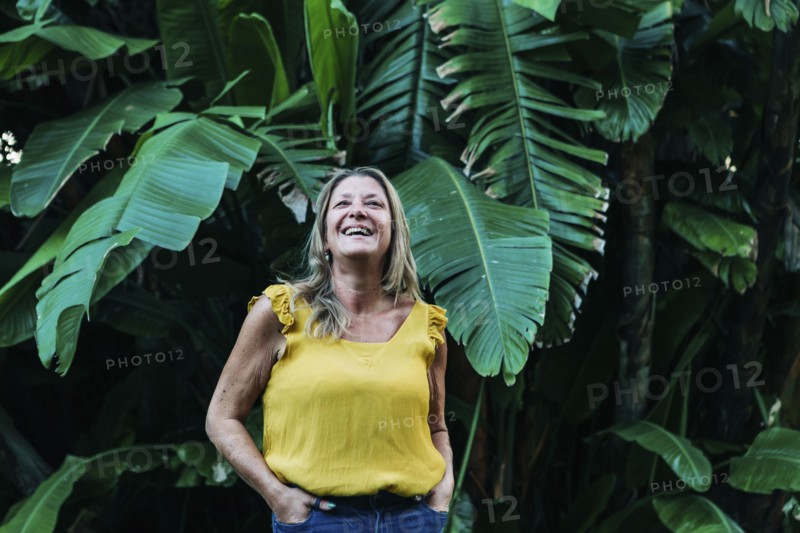 Smiling woman by leaves of palm tree