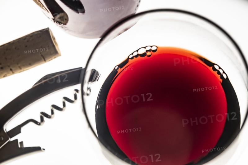 Glass of red wine with corkscrew and cork