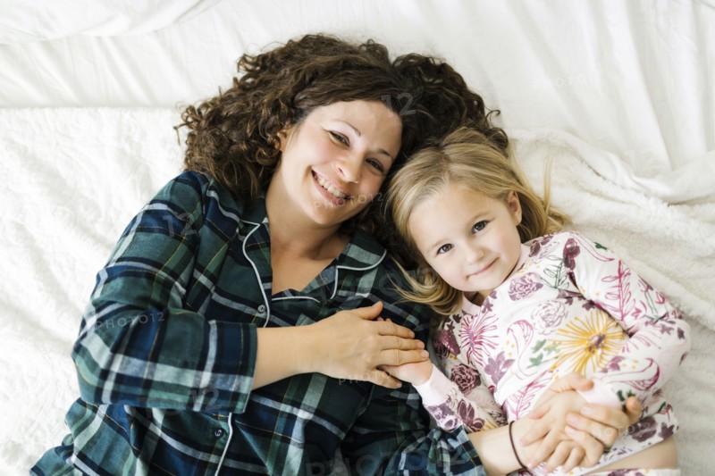 High angle view of mother and daughter in pajamas lying on bed
