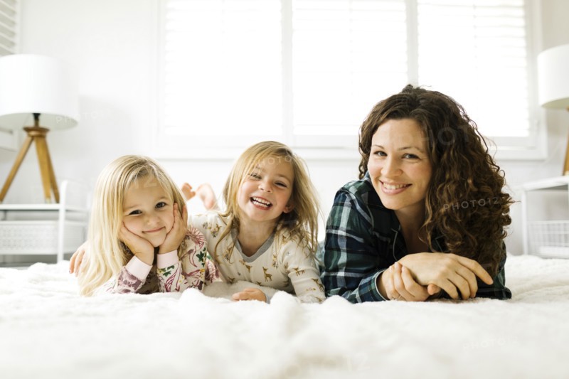 Mother and daughters lying on bed in pajamas