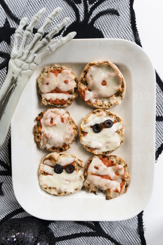 Plate of mini pizzas and hand of Halloween skeleton