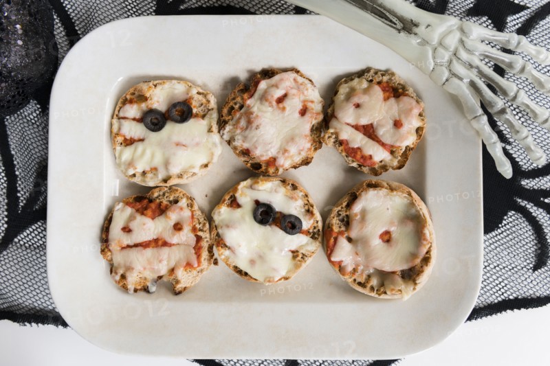 Plate of mini pizzas and hand of Halloween skeleton